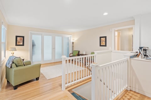 Bright living room with green armchair, wooden flooring, and French doors.