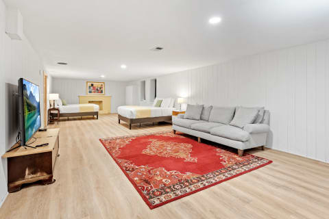 Spacious modern basement room with two beds, a couch, and a television.