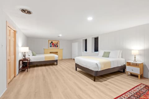 Spacious bedroom with two beds, a lamp, and artwork.