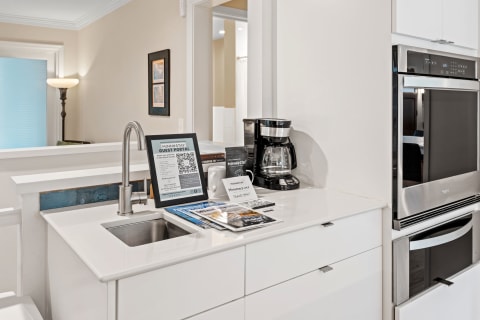 Stylish kitchen countertop with a sink, coffee maker, and a guest portal display.
