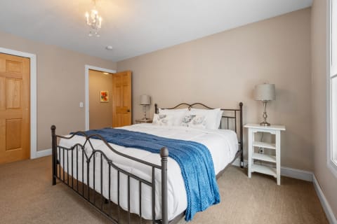 A modern bedroom featuring a metal bed frame with a white comforter and blue throw.