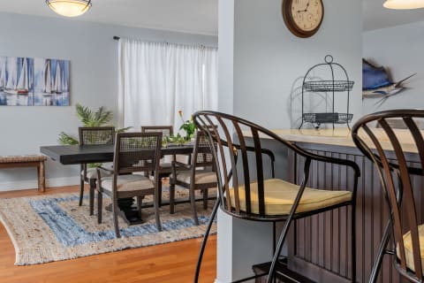 A contemporary dining space featuring dark wood furniture, a marble countertop, and nautical artwork.