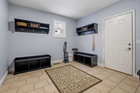Mudroom with blue walls, black storage shelves, and an ornate area rug on tiled flooring.