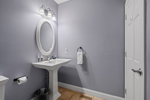 Interior view of a modern bathroom with lavender walls, a white sink, and a mirror.