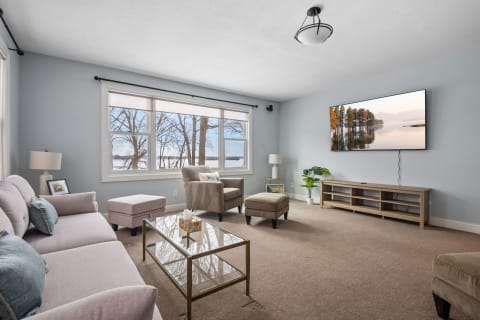 A modern living room featuring a light blue wall, comfortable gray sofa, and a scenic view of nature through large windows.