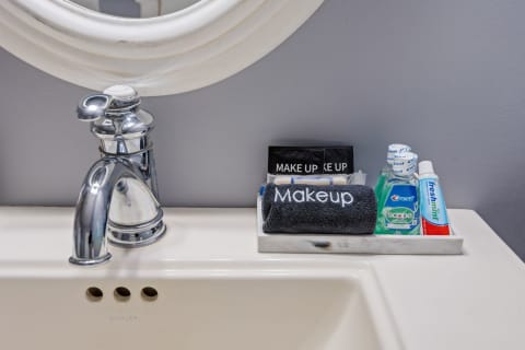 A bathroom sink displaying a chrome faucet, a plush black towel with 'Makeup' text, mouthwash, and toothpaste.