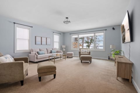 Spacious living room with light blue walls, comfortable seating, and large windows.