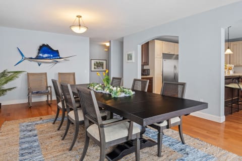 Spacious dining room with a wooden table, chairs, and decorative marlin art on the wall.