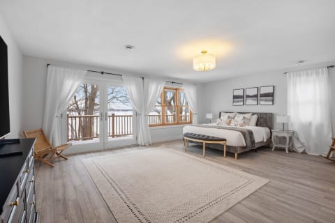 A peaceful bedroom featuring a king-sized bed, large windows, and a stylish interior.