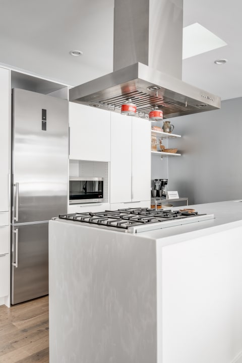 Modern kitchen with a white island, gas stove, and stainless steel refrigerator.