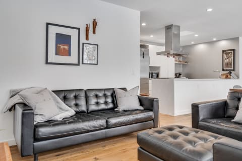 Modern living room with black leather furniture and artistic wall decorations.