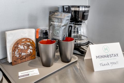 A coffee station featuring mugs, coffee, and a thank-you note in a modern kitchen.