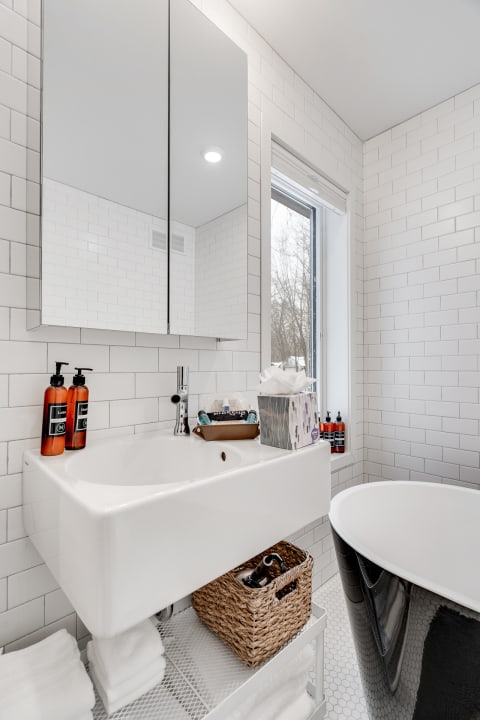 Contemporary bathroom with white subway tiles, sleek sink, and black freestanding bathtub.