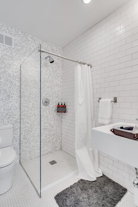 A contemporary bathroom with a glass shower, white tiled walls, and a stylish sink.
