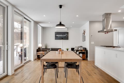 A cozy and modern kitchen and dining area featuring a wooden table, black chairs, and a leather sofa.