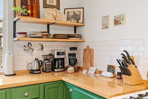A cozy kitchen corner featuring green cabinets, coffee-making equipment, and decorative elements.