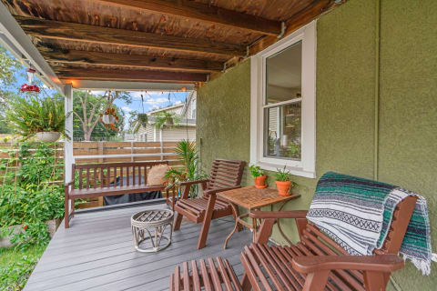 An inviting patio area featuring wooden chairs, a table, and hanging plants under a rustic ceiling.