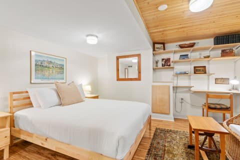 Cozy bedroom featuring a wooden bed, framed artwork, and a stylish bookshelf.