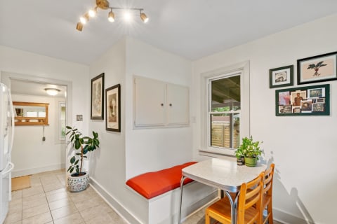 A cozy kitchen nook featuring a red cushion seating area, a round table, and framed art on the walls.