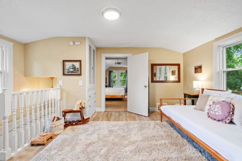 A bright and inviting room featuring a daybed, wooden decor, and a glimpse of greenery outside.