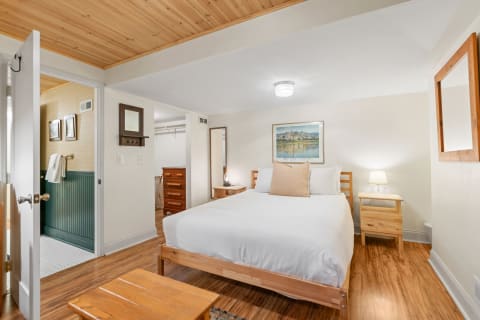 A neatly arranged bedroom featuring a double bed, nightstand, and artwork with natural wood elements.