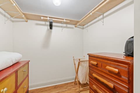 Interior view of a bright, minimalistic closet featuring colorful storage, a towel, a laundry basket, and hangers.