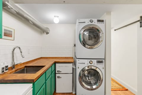 Modern laundry room with stacked washing machines, a vintage refrigerator, and a wooden countertop.