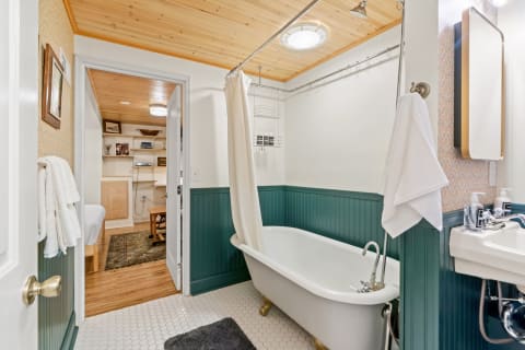A vintage-inspired bathroom featuring a clawfoot tub and green beadboard wainscoting.