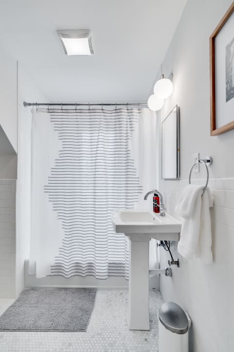 Modern bathroom featuring a pedestal sink, striped shower curtain, and hexagonal tile flooring.