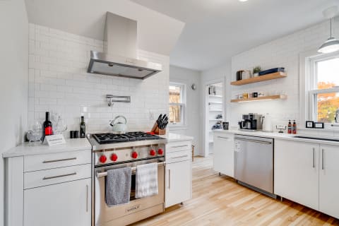 A stylish kitchen with a stainless steel oven, white cabinets, and natural light.