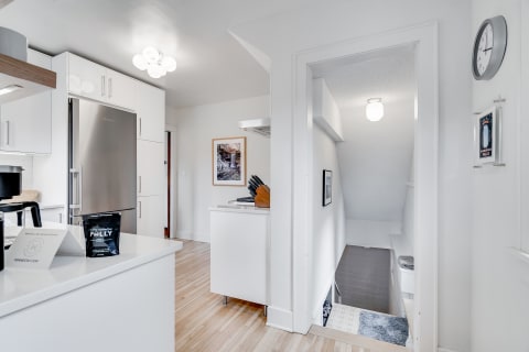Modern kitchen with white cabinets and a staircase in the background.