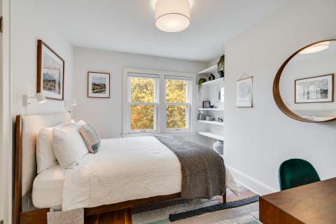 Cozy bedroom with large windows, decorative art, and a stylish desk.