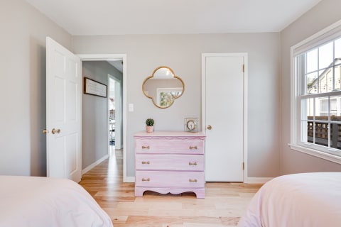 Bedroom with a pink dresser, gray walls, and a window.