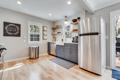 Modern kitchen with gray cabinets, stainless steel appliances, and wooden shelves.