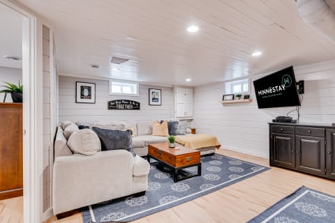 Modern basement living room with a sectional sofa, coffee table, and mounted TV.