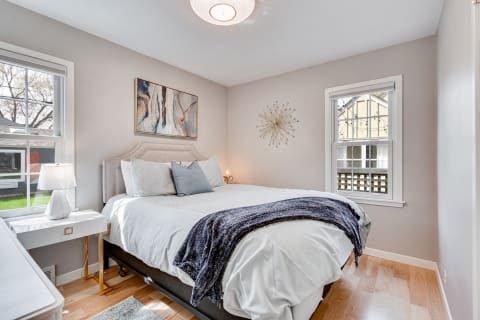 Modern bedroom with a queen-sized bed, abstract art, and natural light.