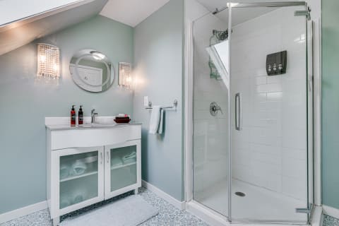 A modern bathroom with a white vanity and glass shower, accented by seafoam green walls.