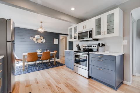 A contemporary kitchen with navy blue cabinets and a dining area.
