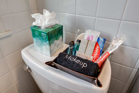 A collection of toiletries and a tissue box arranged on a toilet tank in a bathroom.
