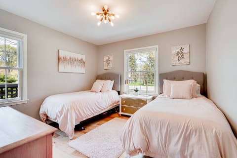 Cozy bedroom with two pink-bedded single beds and a window view.