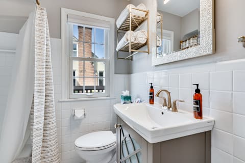A modern bathroom featuring a white vanity, brushed bronze faucet, and neatly arranged towels in a stylish setting.