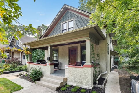 A picturesque house with a covered porch, surrounded by greenery.