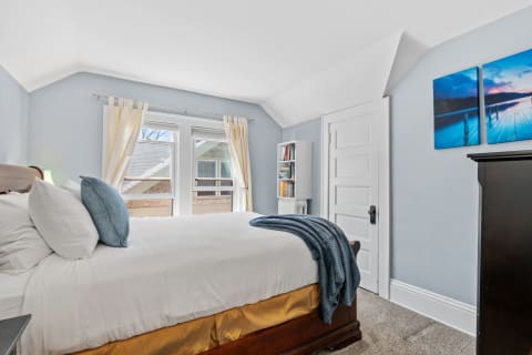 Inviting bedroom with blue walls and a neatly made bed with a blue throw.