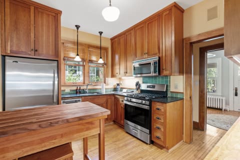 A cozy modern kitchen with wood cabinets, stainless steel appliances, and natural light.