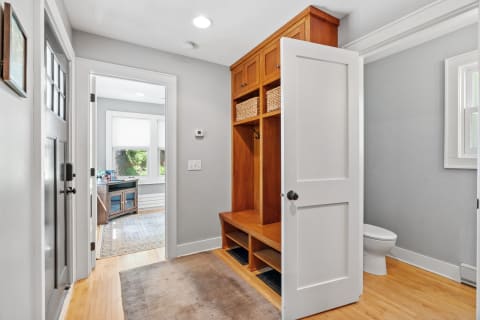 Entryway with wooden mudroom storage and visible desk area in the background.