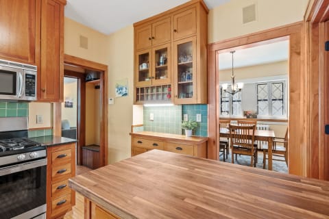 Cozy kitchen showing wooden cabinets and a dining area in the background.
