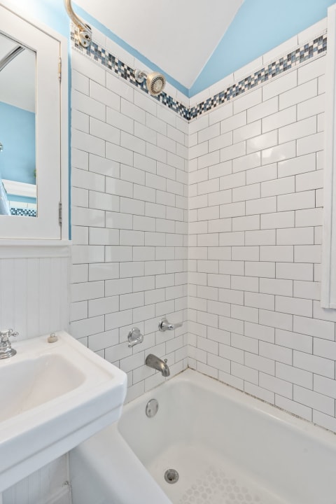 A stylish bathroom corner with white subway tiles, a bathtub, and a showerhead.