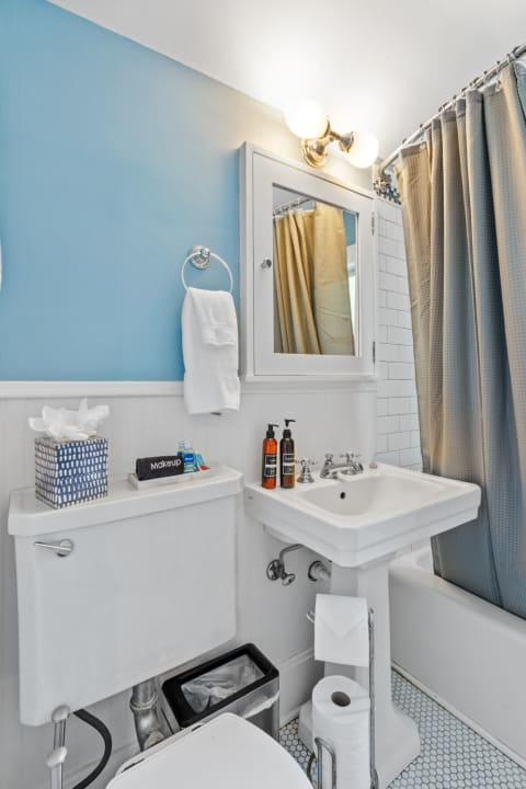 Compact bathroom with light blue walls, wainscoting, and stylish fixtures.
