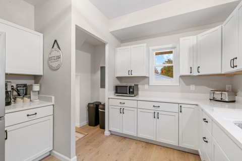 Modern kitchen with white cabinets and a coffee bar setup.