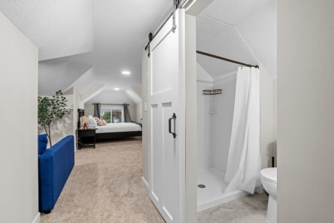 Cozy attic bedroom area featuring a sliding barn door and a minimalist bathroom.
